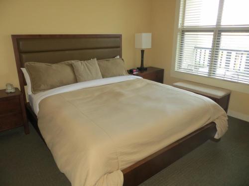 a bedroom with a large white bed with a window at Walnut Beach Resort in Osoyoos