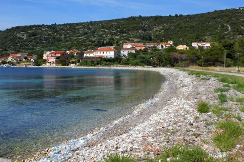 a beach with houses on the shore of a body of water at Apartments and rooms by the sea Cove Soline, Dugi otok - 448 in Veli Rat