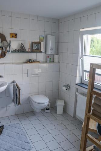 a white tiled bathroom with a toilet and a sink at Deine-Eifel-Ferienwohnung in Feusdorf