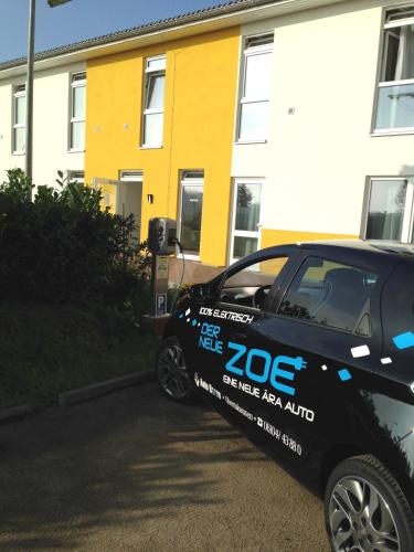 a black car parked in front of a yellow house at i-Motel in Obertshausen