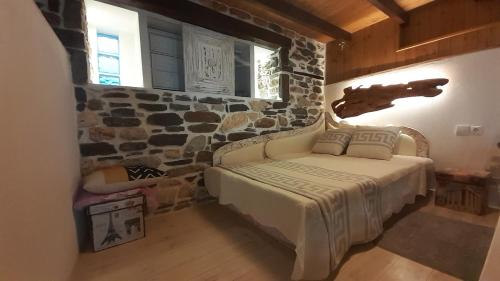 a bedroom with a bed with a stone wall at Relax Holistic House in Potamiá