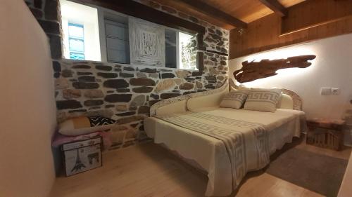 a bedroom with a bed with a stone wall at Relax Holistic House in Potamia