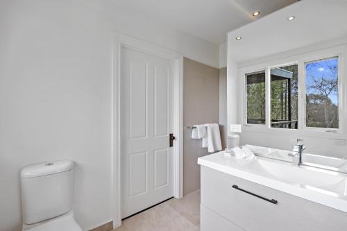 uma casa de banho branca com um lavatório e um espelho em Old Fernshaw Cottage em Healesville