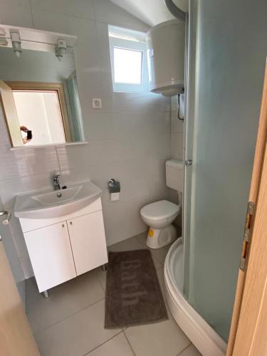 a white bathroom with a sink and a toilet at Villa nad Morem in Podaca