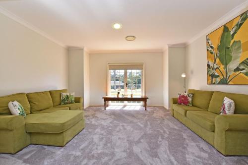 a living room with two couches and a table at Hunter Winery Hideaway with Pool & Games Room in Nulkaba