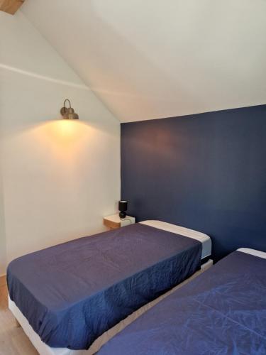 1 dormitorio con 2 camas y pared azul en Villa Nomy, en Grandes Sables