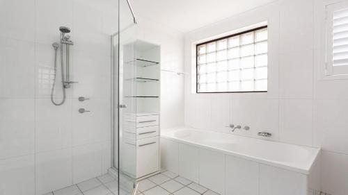a white bathroom with a tub and a glass shower at Surfspray 4 Pebbly Beach in Forster