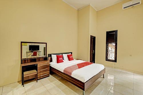 a bedroom with a bed and a dresser and a mirror at OYO 91522 Candi Gebang Guesthouse in Seturan