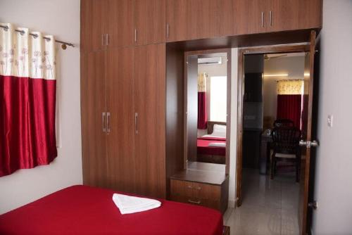 a bedroom with a red bed and a mirror at The Vihar service Apartment in Mysore