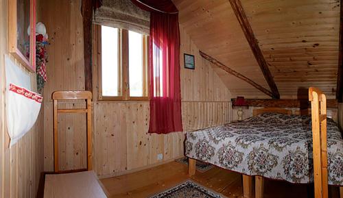 una camera con un letto in una cabina di legno di Yasna Sadyba a Yasenitsa Zamkova