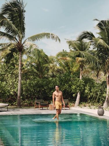 a man standing in the water in a swimming pool at Patina Maldives, Fari Islands in North Male Atoll