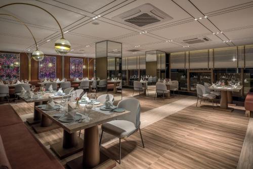 a restaurant with tables and chairs in a room at Oakwood Premier Phnom Penh in Phnom Penh