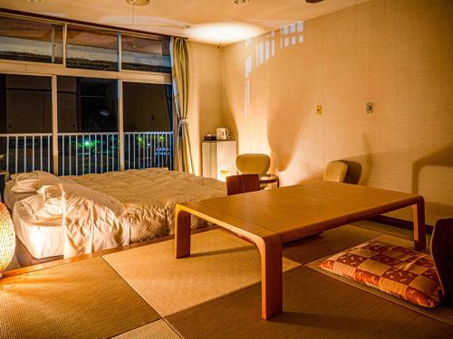 a bedroom with a bed and a table and a window at Kameyama Onsen Hotel in Kimitsu