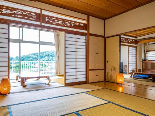 a room with a large window and a door with a view at Kameyama Onsen Hotel in Kimitsu