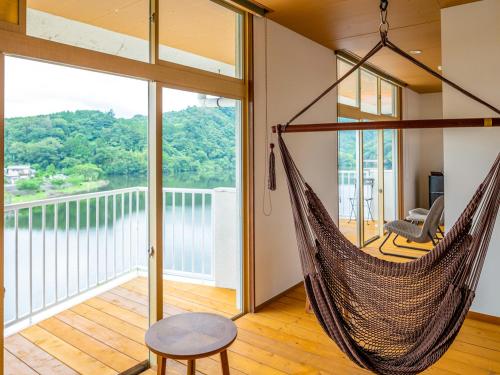 a hammock in a room with a view of the water at Kameyama Onsen Hotel in Kimitsu
