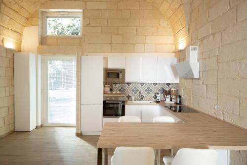 uma cozinha com uma mesa de madeira e armários brancos em DonCarlo Suite Relais - Free Parking-parcheggio gratuito em Lecce