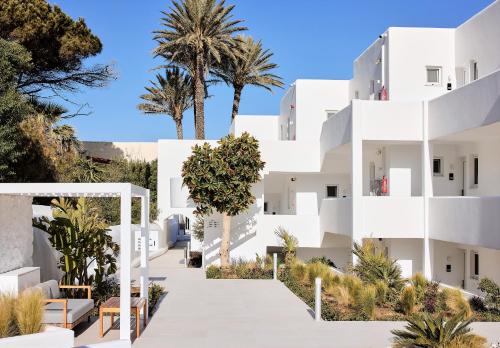 a white building with palm trees in the background at Kantouni Beach Boutique Hotel in Panormos Kalymnos