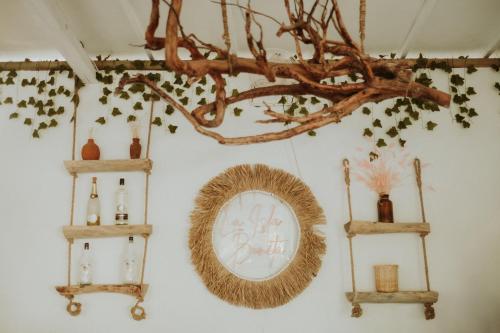 a wall with two shelves and a mirror and a tree branch at La Isla Bonita Gili Air in Gili Air