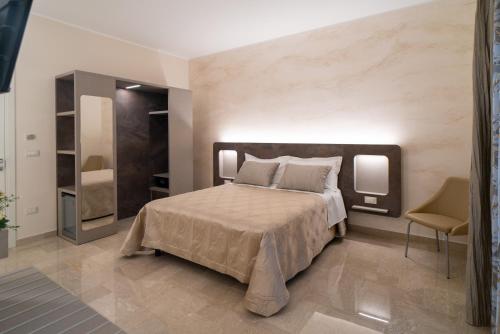 a bedroom with a large bed and a chair at Le margherite B&B in Mesagne