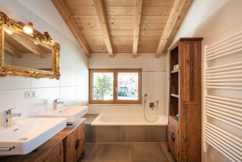 a bathroom with two sinks and a tub and a mirror at Ski in - Ski out Panoramaferienhaus Breitmoos neben Mittelstation in Mittersill