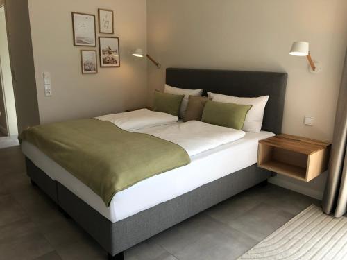 a bedroom with a large bed with white sheets and green pillows at Gästehaus Muhl in Strukkamp auf Fehmarn
