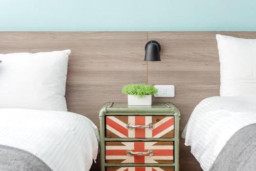 a bedroom with two beds and a plant on a night stand at DoGoo in Kaohsiung