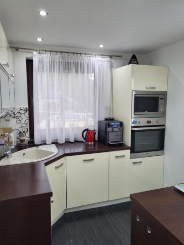 a kitchen with white cabinets and a sink and a microwave at Chata Valca PATJA-v mesiacoch apríl až november pri prenajatí aj jedného apartmánu uzavrieme ostatné apartmány, aby ste si užili súkromie in Valča