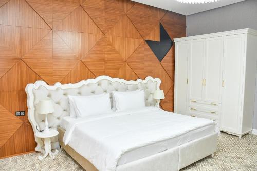 a bedroom with a white bed with a wooden wall at Ramada by Wyndham Turkistan in Türkistan