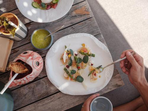 a person eating food on a table with plates of food at Patina Maldives, Fari Islands in North Male Atoll