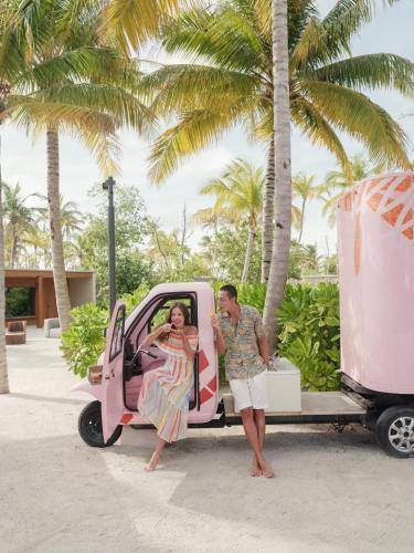 a man and woman getting out of a pink car at Patina Maldives, Fari Islands in North Male Atoll