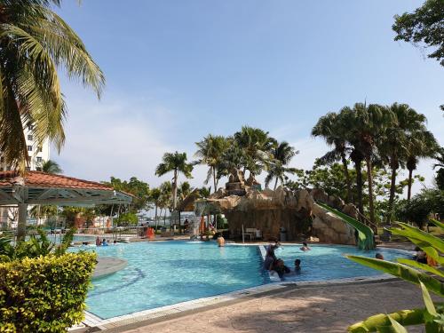 a pool at a resort with people playing in it at 99 Glory Beach Resort - seaview, poolview, beachfront,wifi in Seremban