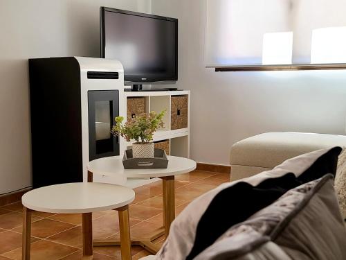 - un salon avec une télévision, un canapé et une table dans l'établissement El Escondite de Gredos, à Lanzahita
