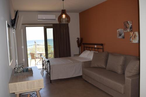 ein Schlafzimmer mit einem Bett und einem Sofa sowie einem Balkon in der Unterkunft Αιγιαλίς - Πολυτελη διαμερισματα in Karystos