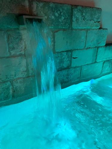 a waterfall in a swimming pool with a stone wall at Palazzo Vecchio Cocumola in Cocumola