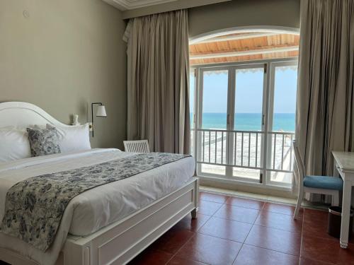 a bedroom with a bed and a balcony with the ocean at Villa Cavi in Puducherry