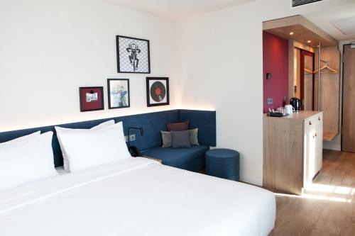 雷根斯堡Hampton By Hilton Regensburg的卧室里有一张白色的床和一张蓝色的沙发