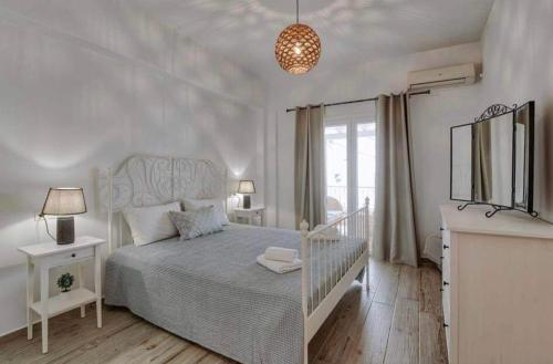 a white bedroom with a bed and a window at GARBIS HOUSE ( Antiparos Main Street ) in Andiparos