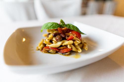 a plate of pasta with olives and basil on a table at Hotel Villa Sara in Mestre