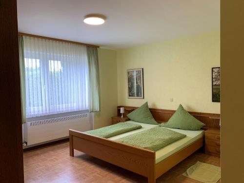 Un dormitorio con una cama con almohadas verdes y una ventana en Haus Berndorf en Berndorf