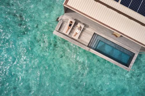 two people standing on a boat in the water at Patina Maldives, Fari Islands in North Male Atoll