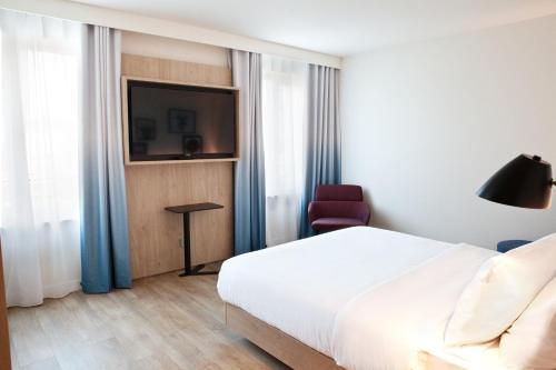 a bedroom with a bed and a tv and a chair at Hampton By Hilton Regensburg in Regensburg