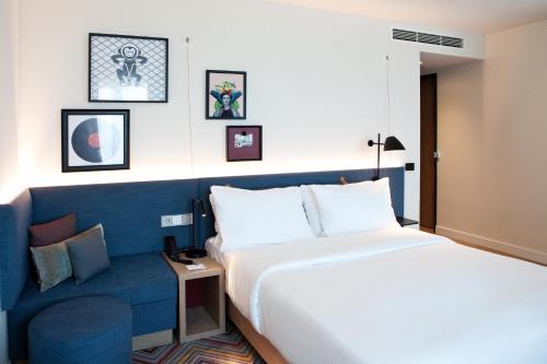 a hotel room with a bed and a blue couch at Hampton By Hilton Regensburg in Regensburg