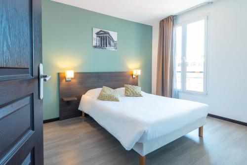 1 dormitorio con cama blanca y ventana en Zenitude Hôtel-Résidences Nîmes Centre en Nimes