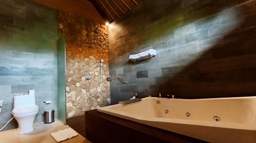 a bathroom with a bath tub and a toilet at Puri Andong Villa in Ubud