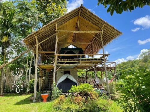 a tree house with a grill in the grass at Chiang Dao Hostel in Chiang Dao