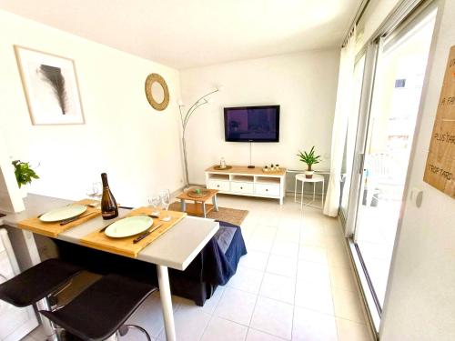 - une salle à manger avec une table et une télévision dans la chambre dans l'établissement 2P 42m² Terrasse / Piscine / Clim / Plage !, à Juan-les-Pins