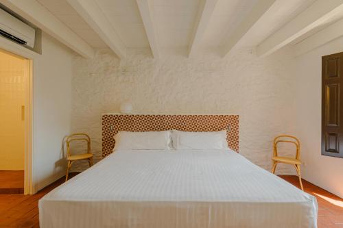 un letto bianco in una stanza con due sedie di Flateli Santa Clara 22 a Girona