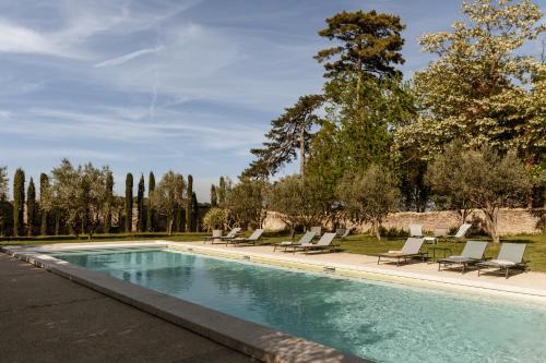 a swimming pool with chaise lounge chairs and trees at Le Domaine de L'Osage in Pont-Saint-Esprit