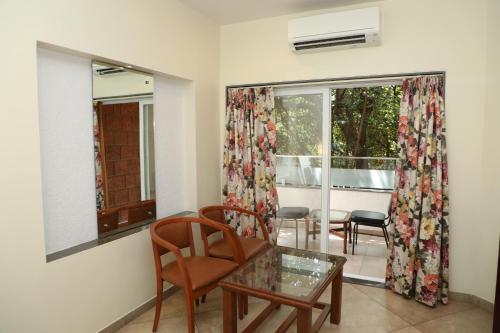 a living room with a table and chairs and a window at Bella Vista Mahabaleshwar in Mahabaleshwar
