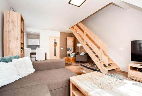 a living room with a couch and a staircase at Apartmán s terasou in Říčky